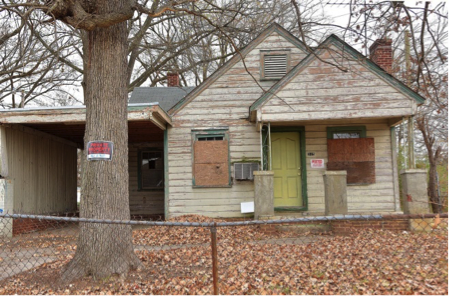 abandoned, boarded-up house in deteriorated condition